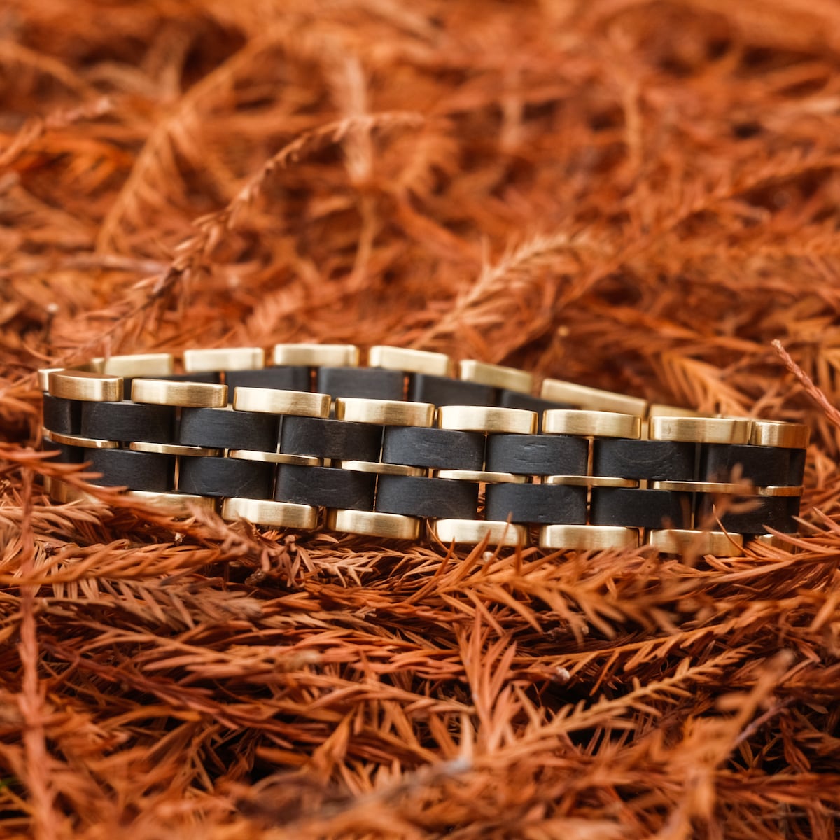 "Kanon" bracelet in black maple and gold, showcasing elegant craftsmanship and rustic style.