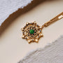 "Aphonia Necklace" necklace with a green marble centerpiece set in gold, featuring an intricate design pattern.