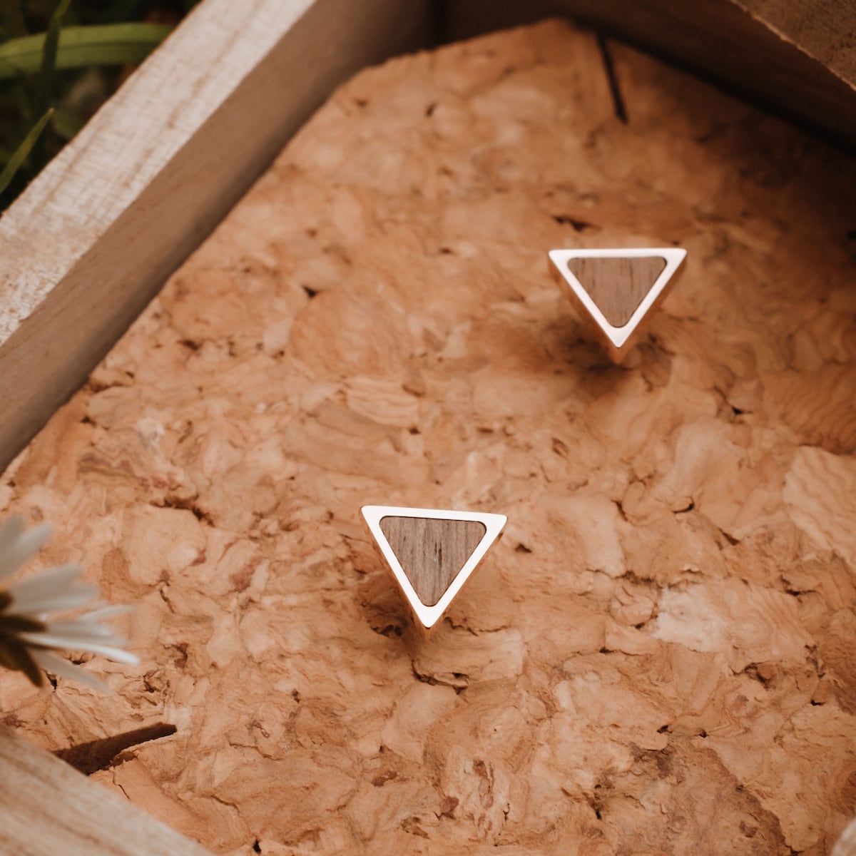"Scale Earrings" – triangular earrings in walnut and rose gold, showcasing elegant, modern design on a textured background.