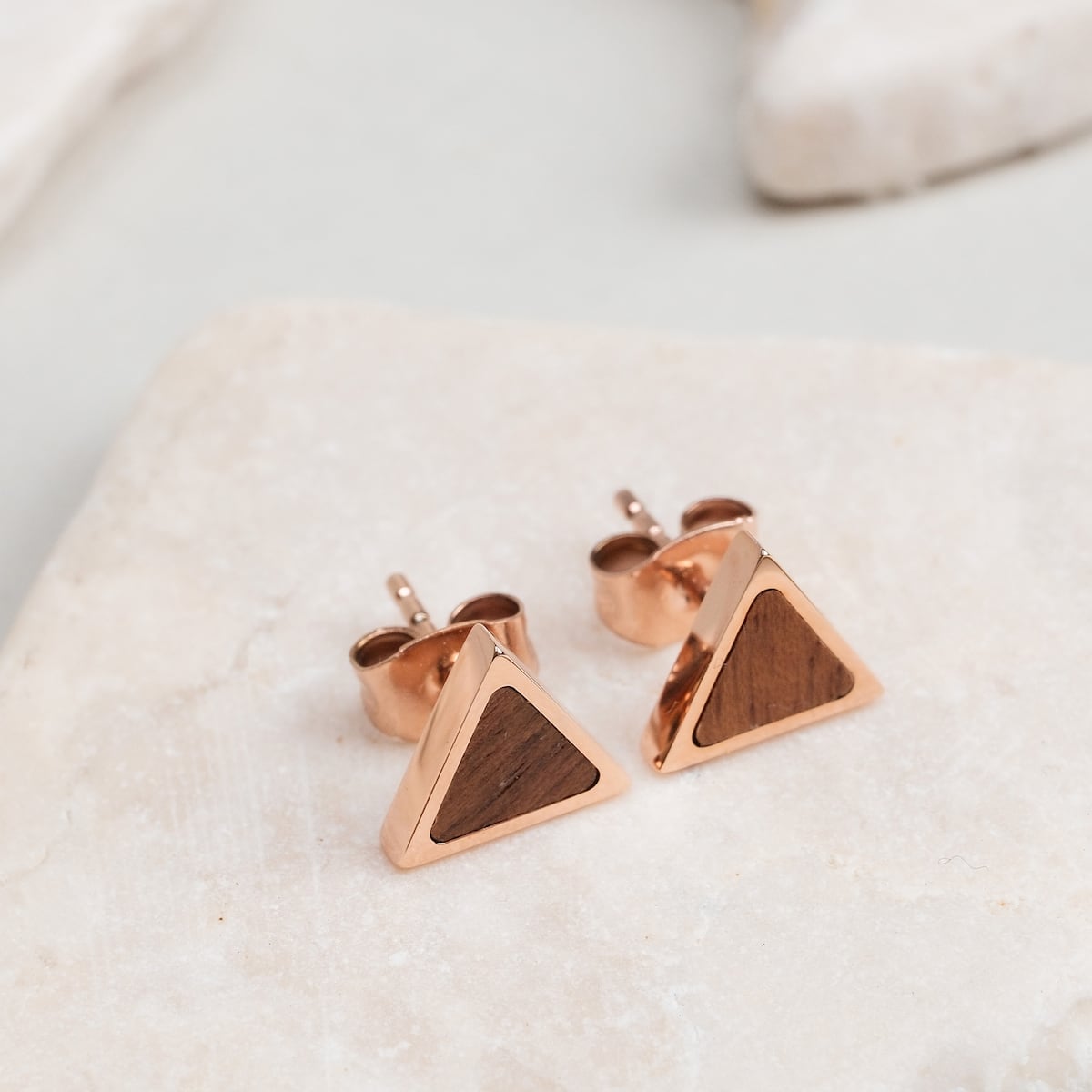 "Scale Earrings" earrings featuring walnut and rose gold in a triangular design on a neutral background.