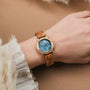 "Antrim" wristwatch featuring a wooden band and blue dial, stylishly worn on a wrist.