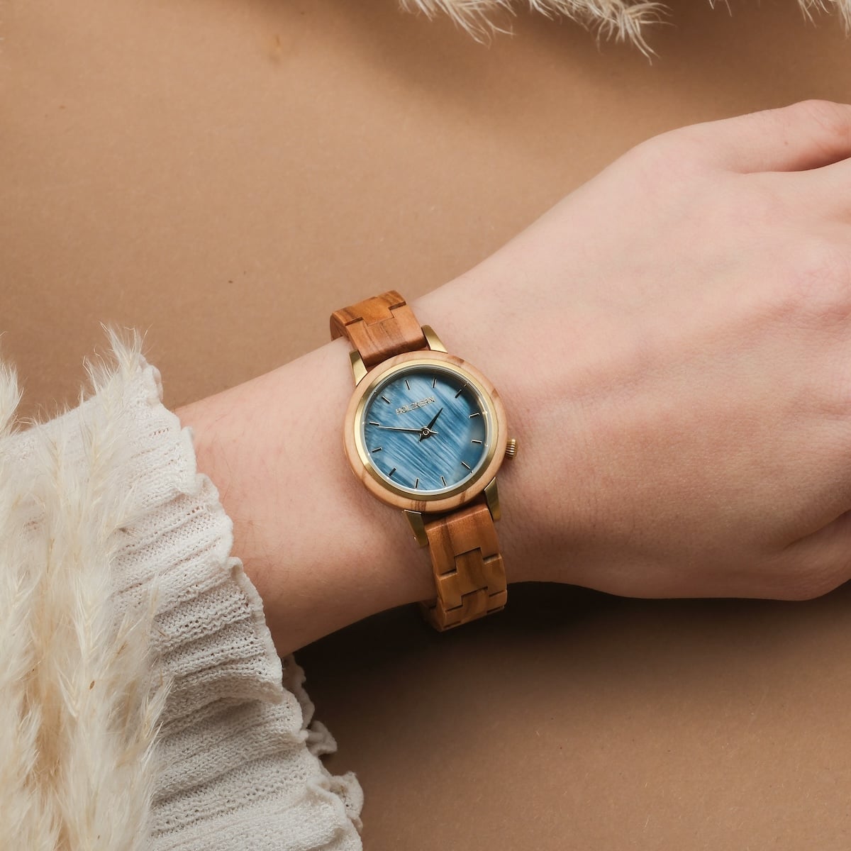 "Antrim" wristwatch featuring a wooden band and blue dial, stylishly worn on a wrist.