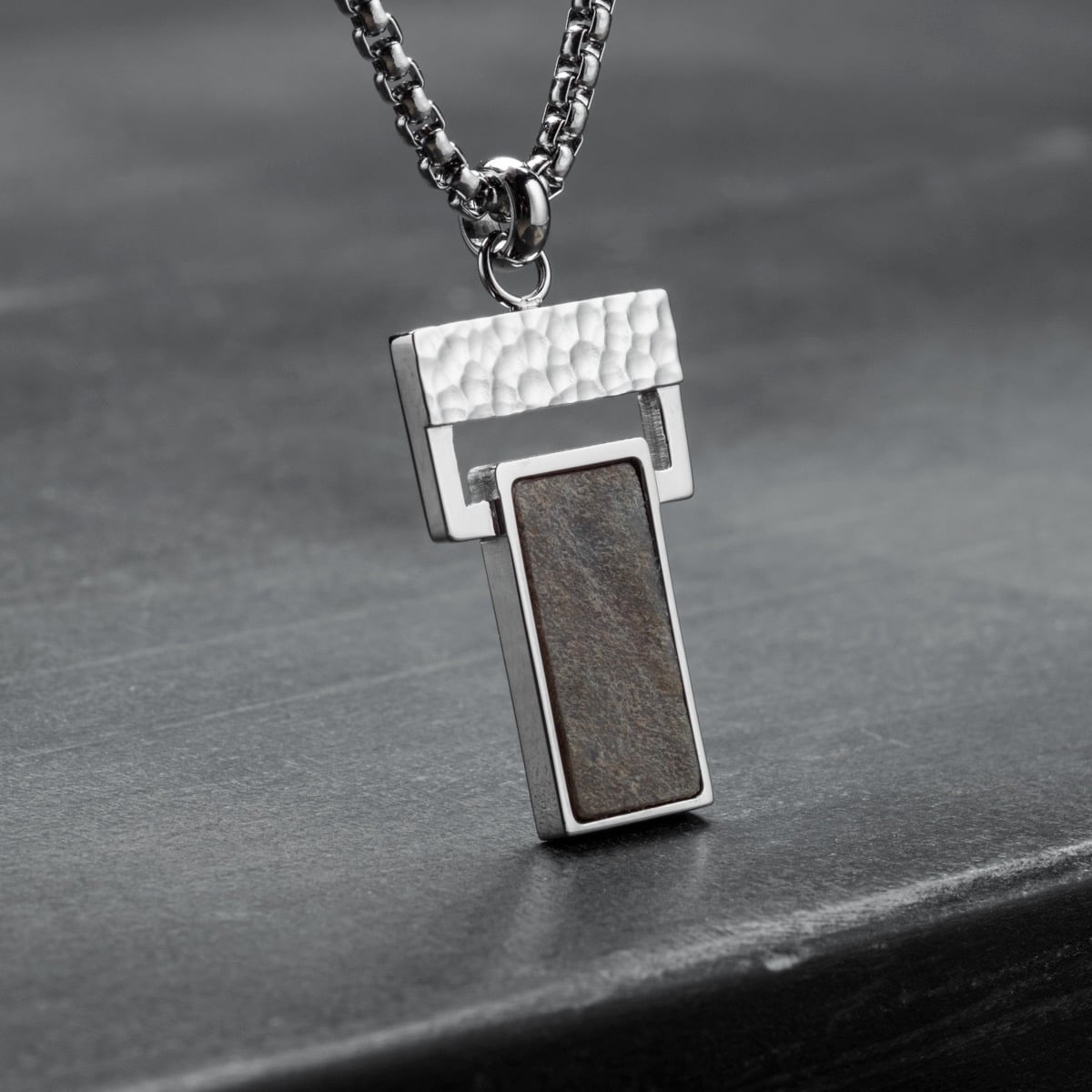 "Transcendent" necklace featuring a slate and silver design with a modern, textured style.