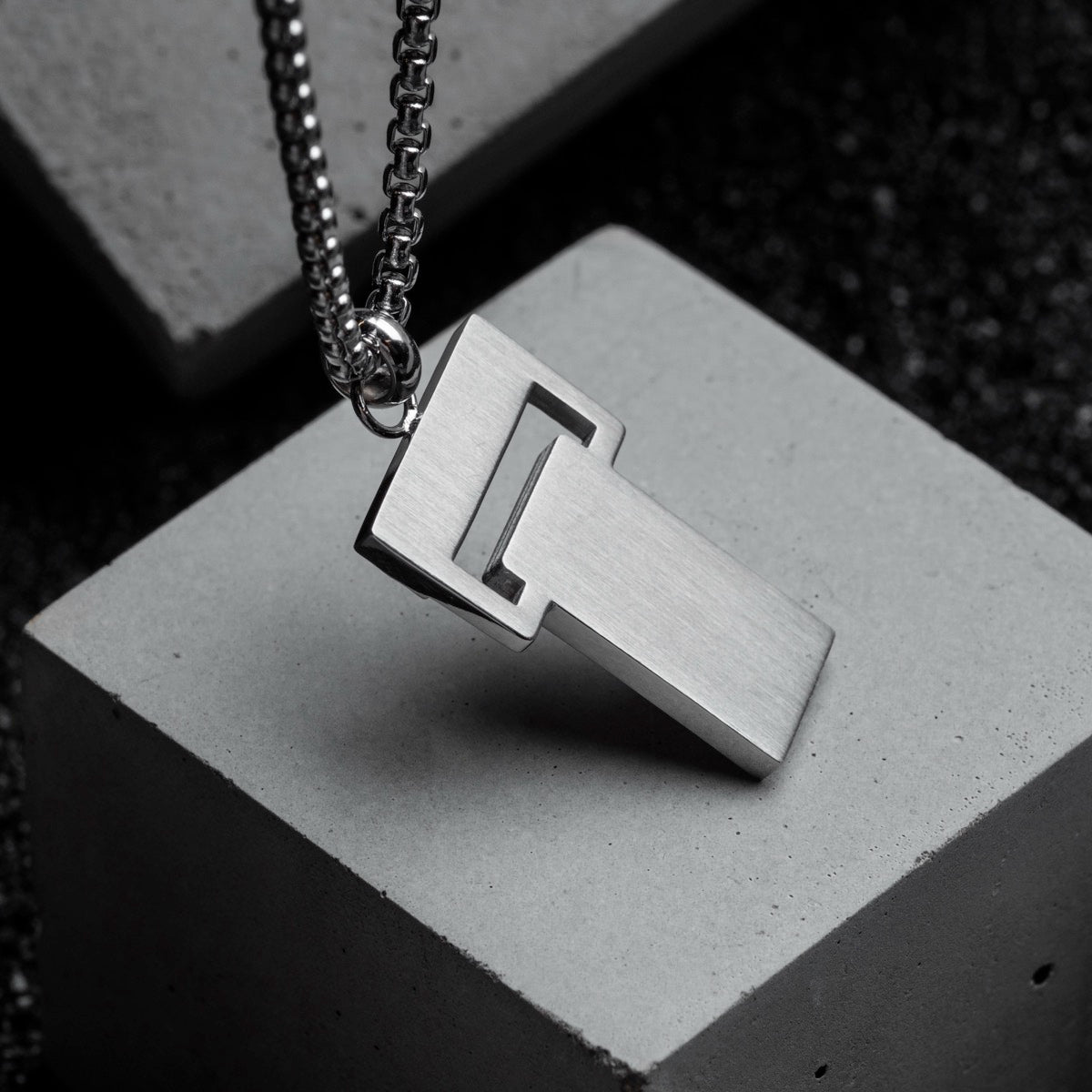 "Transcendent" pendant in slate and silver, featuring a minimalist geometric design.