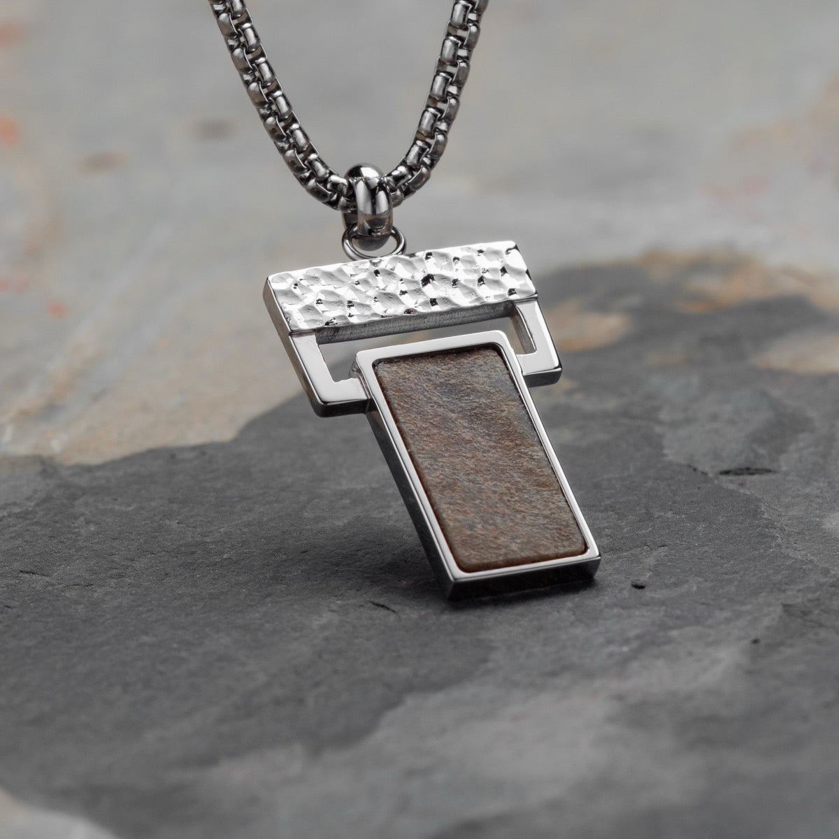"Transcendent" necklace featuring a slate and silver design with a textured, modern aesthetic.