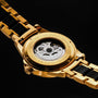 "Flowfinder", a stylish watch with a maple and gold finish, featuring an intricate mechanical back design.