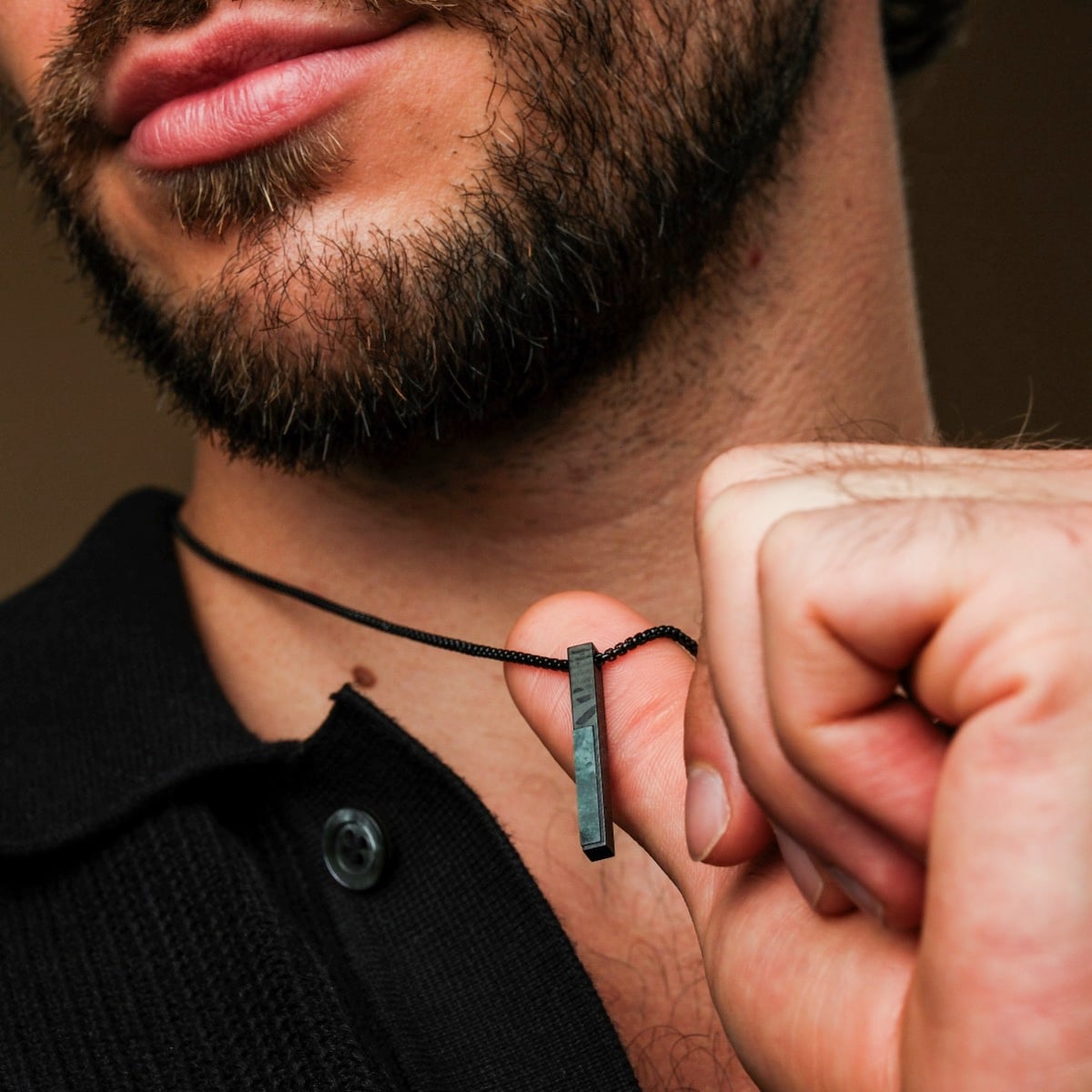 "Campania Necklace" necklace featuring green marble and Damascus steel, showcased against a dark shirt for a stylish look.