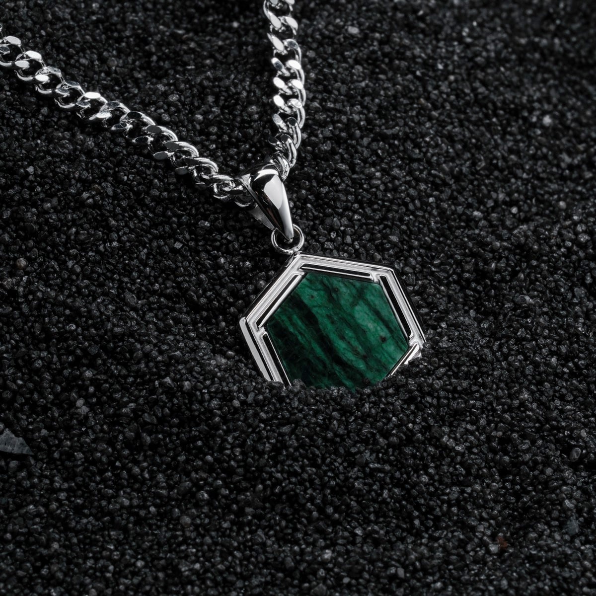 "Axis Necklace" is a silver necklace with a green marble pendant, showcasing a modern geometric design.