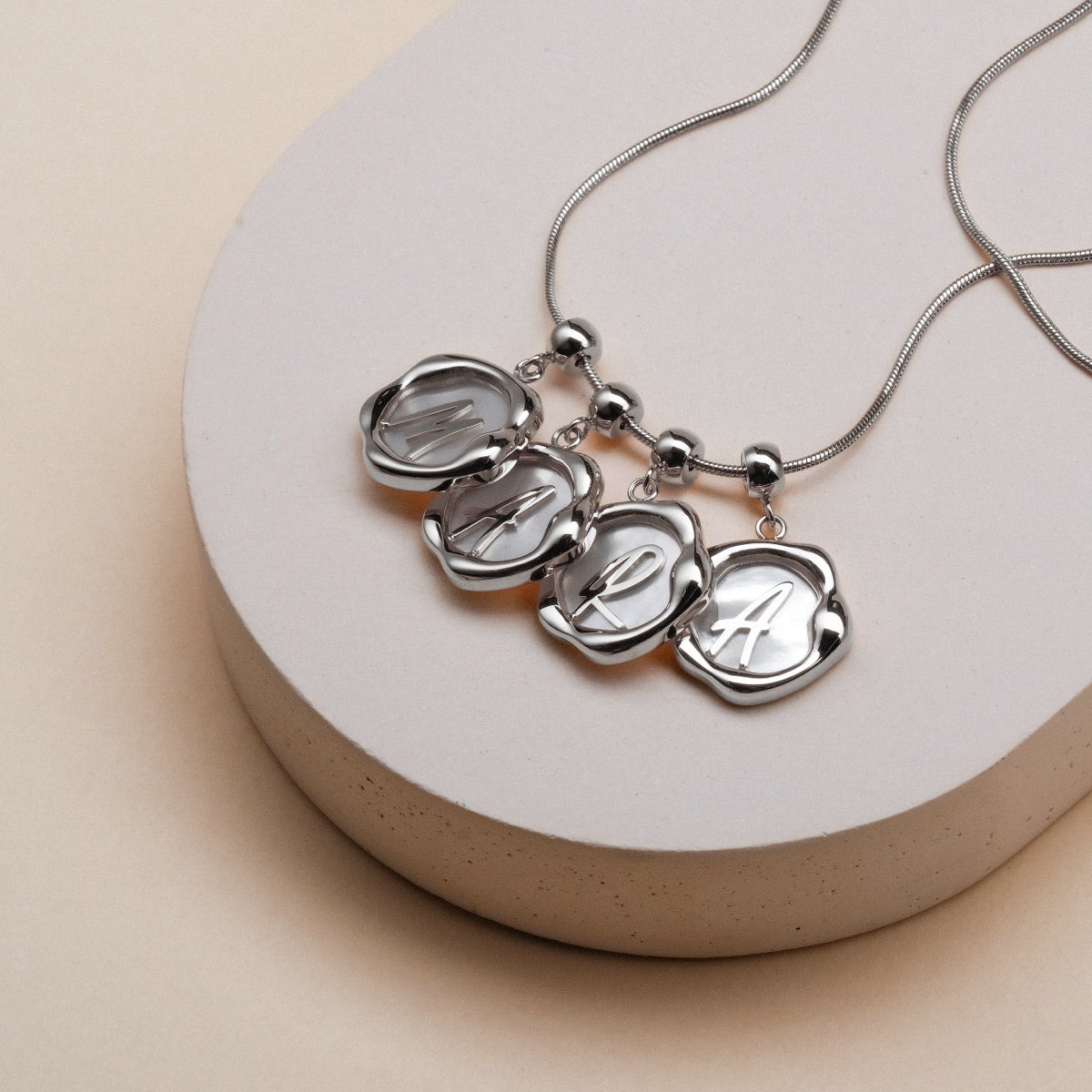 "Letter Charm A-Z" necklace featuring elegant, nacre and silver letter charms in a refined style.