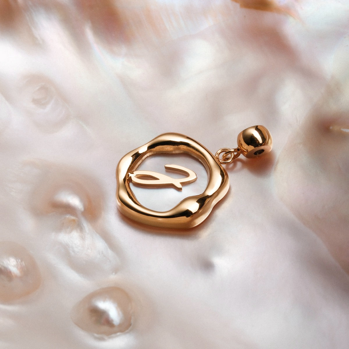 "Letter Charm A-Z" gold letter charm on nacre background, elegant and stylish design.