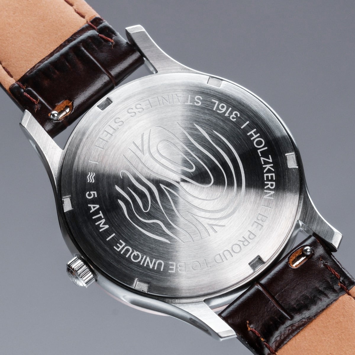 "Moonrise" wristwatch with a marble face and dark brown leather strap, featuring a stainless steel case back design.