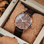"Gifted" wristwatch with a walnut face and dark brown leather strap, featuring a luxurious, rustic design in a wooden box.