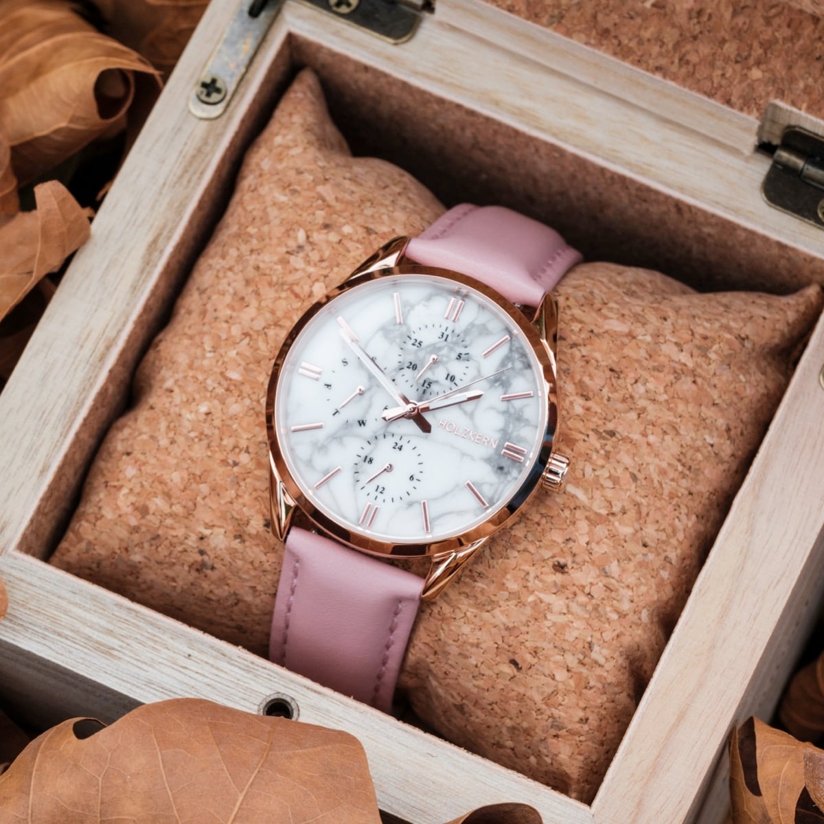 "Gifted", an elegant watch with a marble-style face and pink strap, displayed in a wooden box.