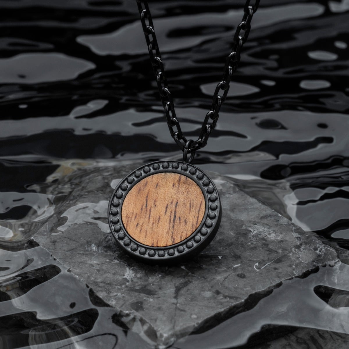 "Interplay Necklace" necklace featuring a round Koa wood pendant with a gray beaded metal border.