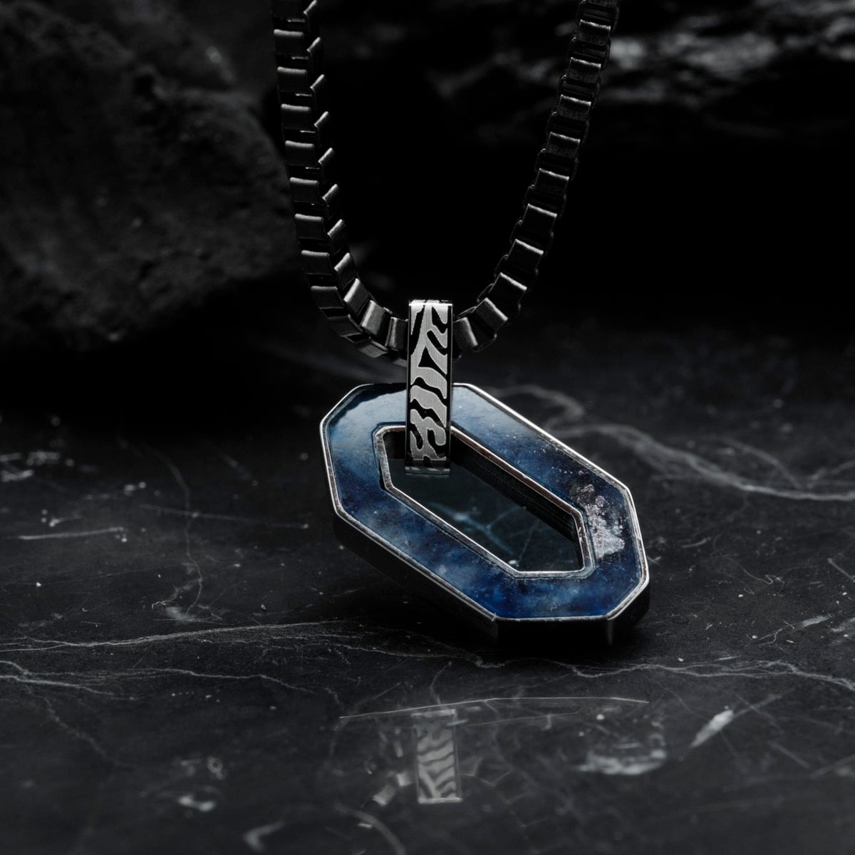 "Interplay Necklace" necklace, featuring sodalite and Damascus steel, on a sleek, dark background for a bold and artistic look.