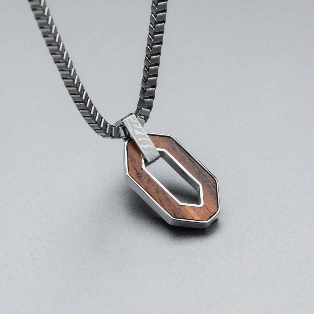 "Interplay Necklace" necklace featuring a geometric pendant in walnut and Damascus steel for a modern, stylish look.