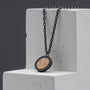 "Interplay Necklace" necklace featuring a round koa wood pendant with black chain, showcasing a modern and earthy style.