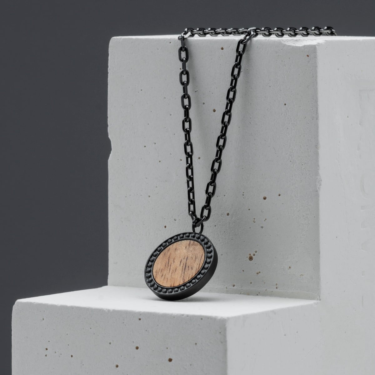 "Interplay Necklace" necklace featuring a round koa wood pendant with black chain, showcasing a modern and earthy style.