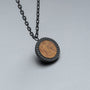 "Interplay Necklace", a stylish pendant necklace with a koa wood design and a sleek gray chain.