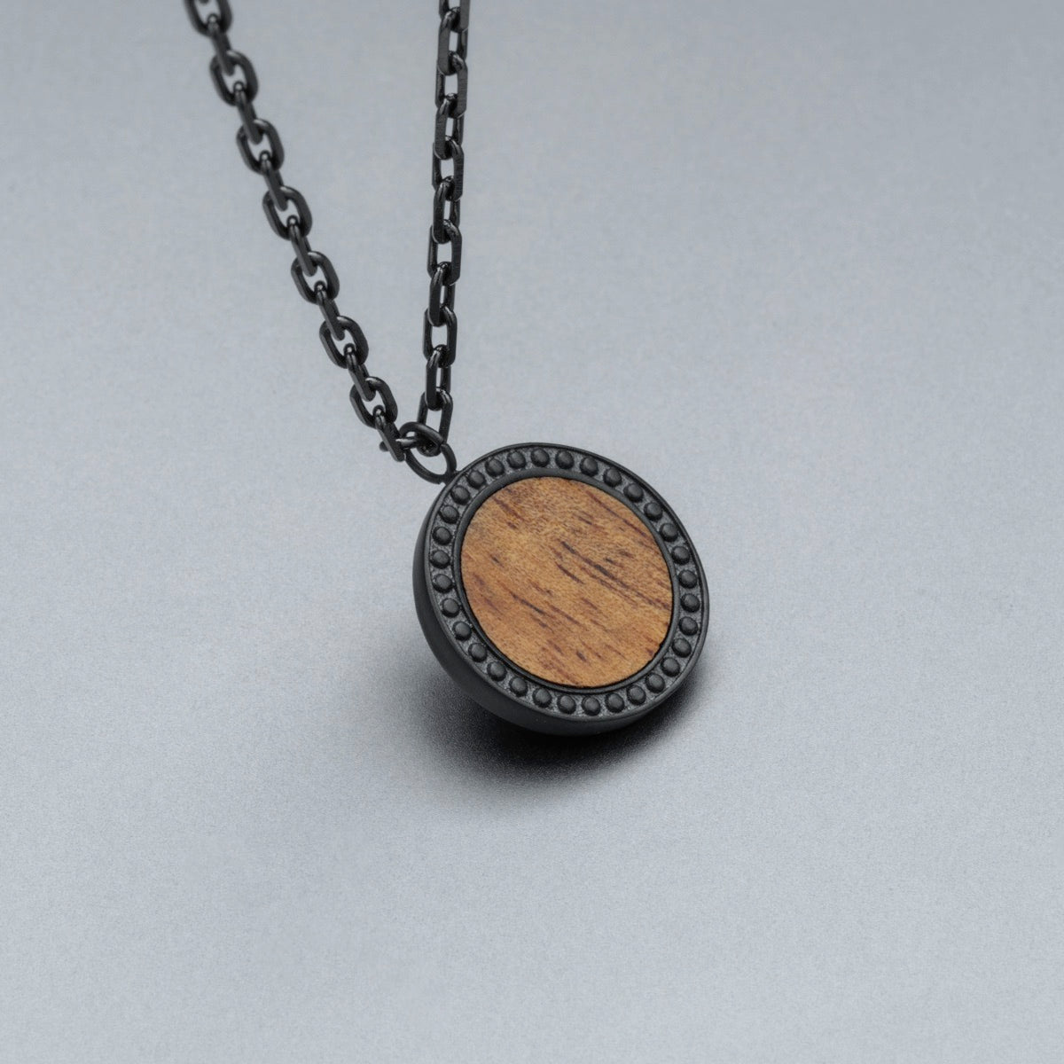 "Interplay Necklace", a stylish pendant necklace with a koa wood design and a sleek gray chain.