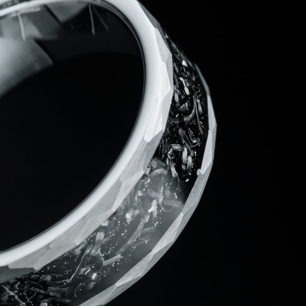 "Sumo Ring" ring crafted from meteorite and tungsten, showcasing a textured and intricate design against a sleek black background.