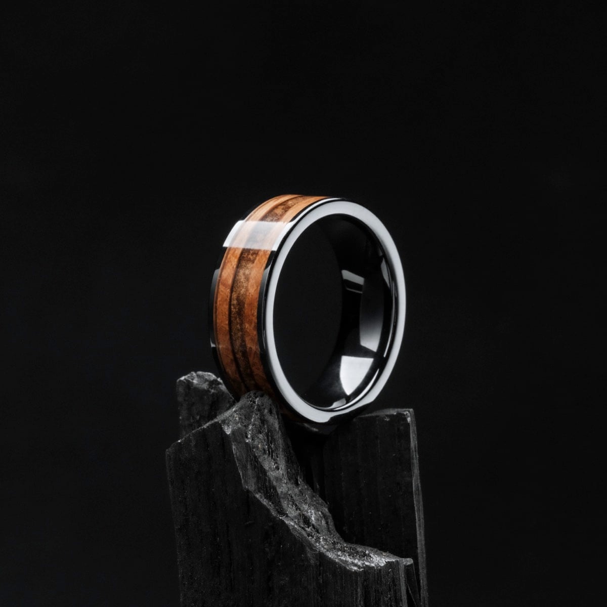 "Sumo Ring"--A ring crafted in whiskey wood and ceramic, set against a dark, sophisticated backdrop.