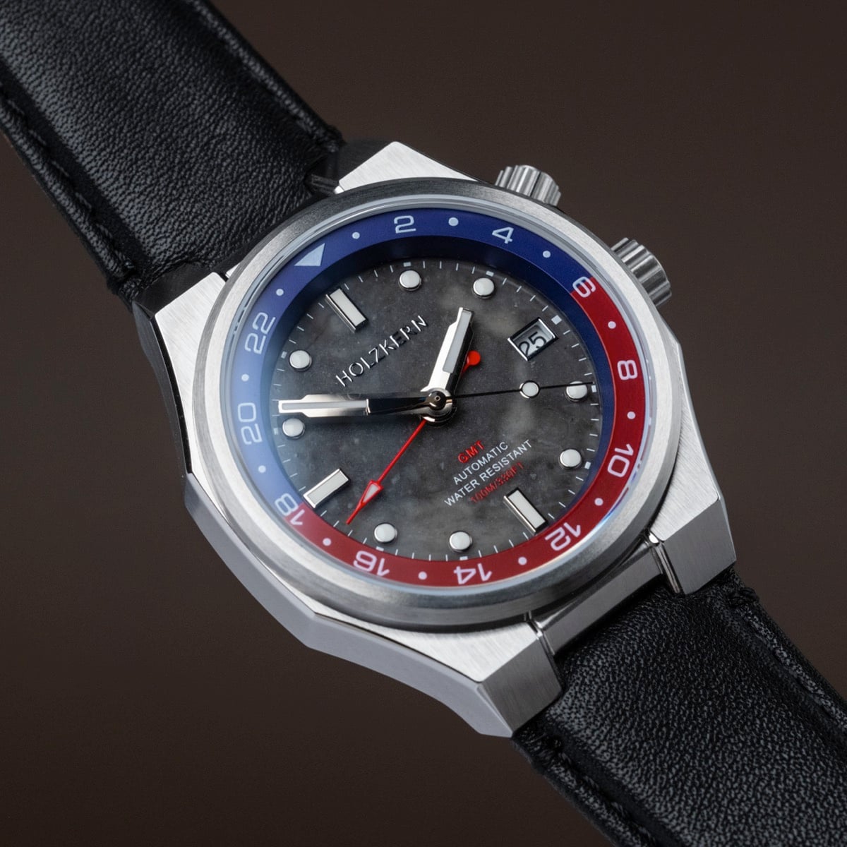 "GMT Cloudhopper" watch with a marble/black dial and two-tone bezel, featuring a sleek, modern design.