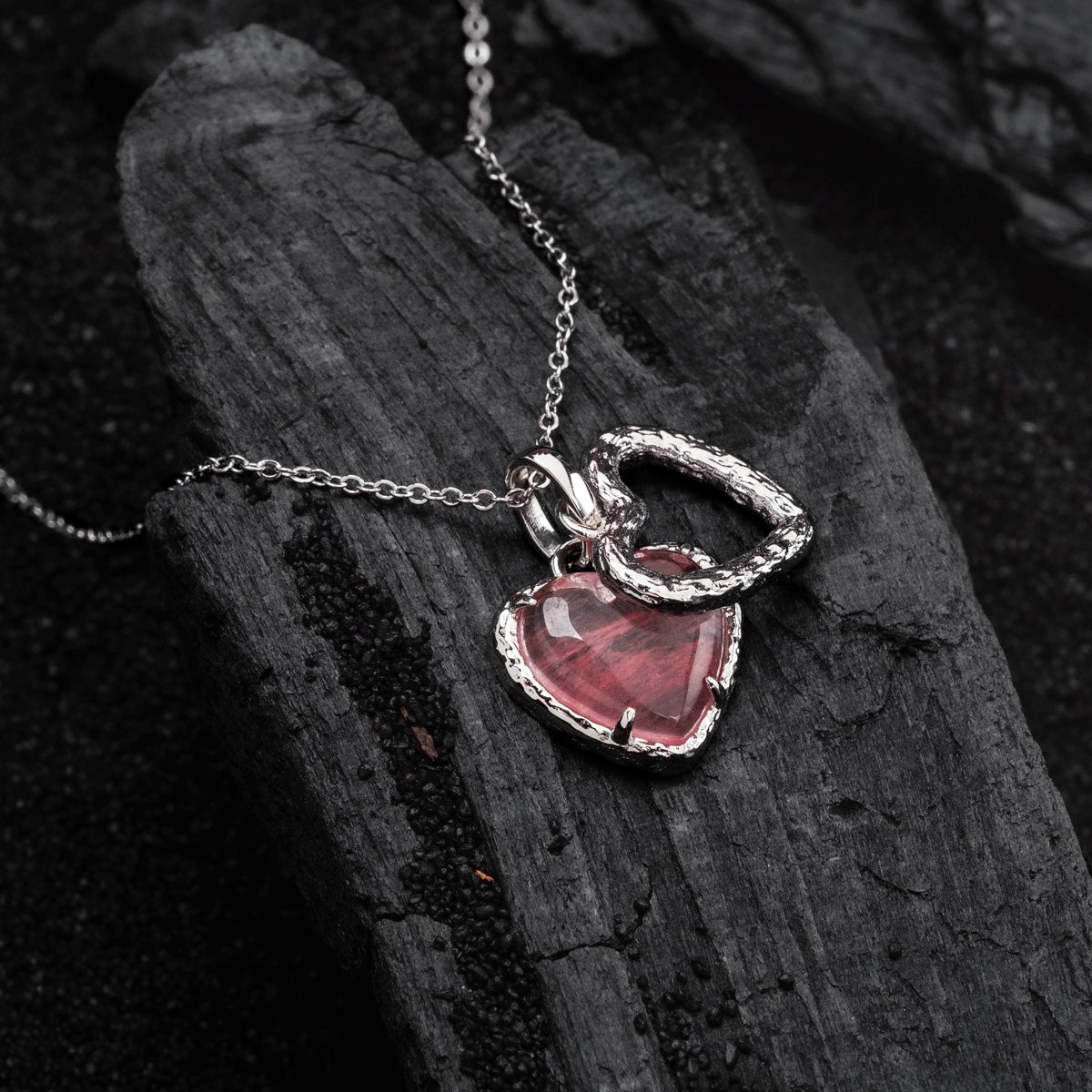 "Amorance Necklace", a heart-shaped quartz and silver necklace, elegantly displayed on dark textured background.