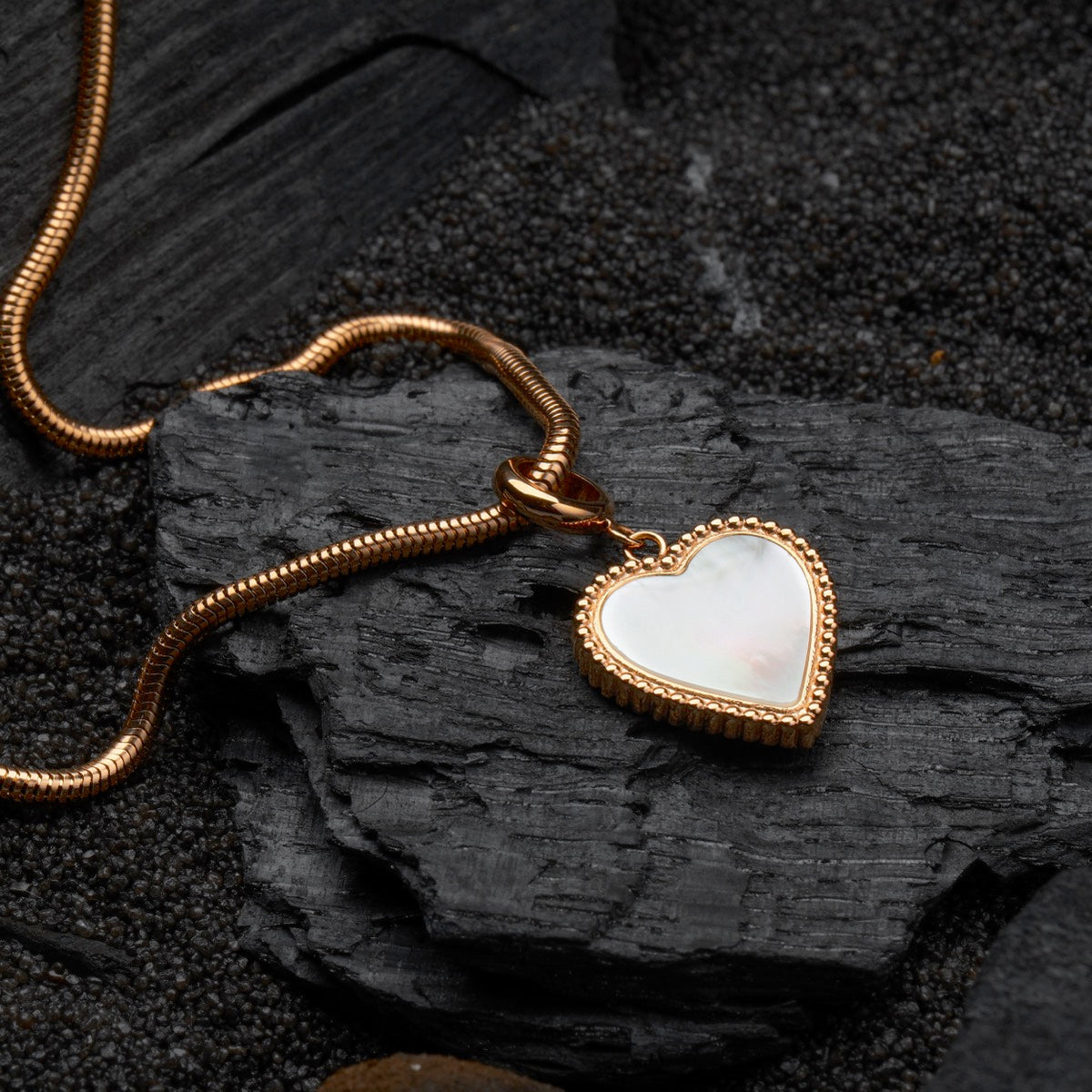 "Amorance Necklace", a stylish necklace featuring a heart-shaped nacre pendant and rose gold chain on a dark textured background.