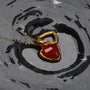 "Amorance Necklace", a gold chalcedony heart necklace with a textured finish on a reflective surface.