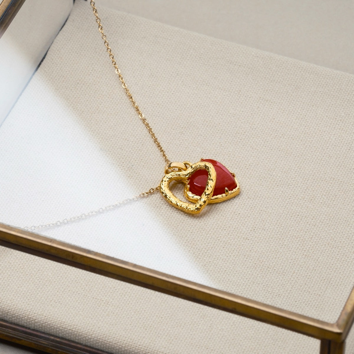 "Amorance Necklace", a gold chalcedony necklace with intertwined heart pendants on a delicate chain, exudes elegance and charm.