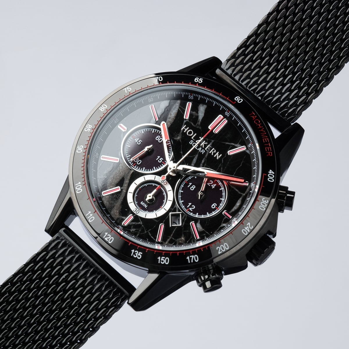 "Comfort Crusher" watch features a sleek marble and black design with a mesh band and detailed chronograph face.