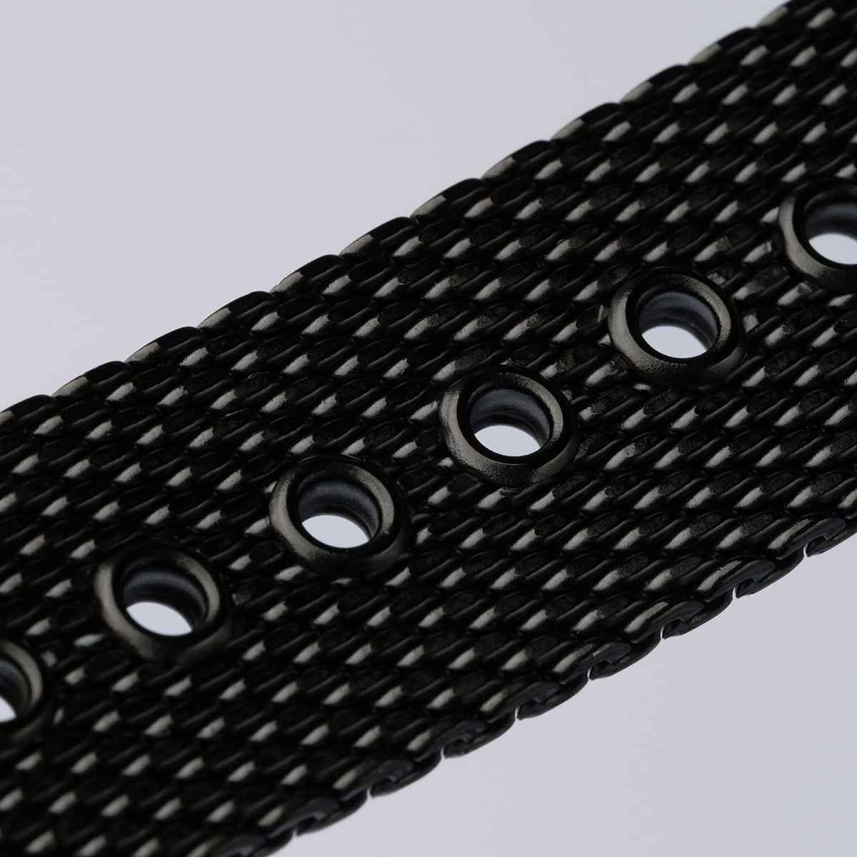 "Comfort Crusher", a black textured belt with circular holes and marble design accents.