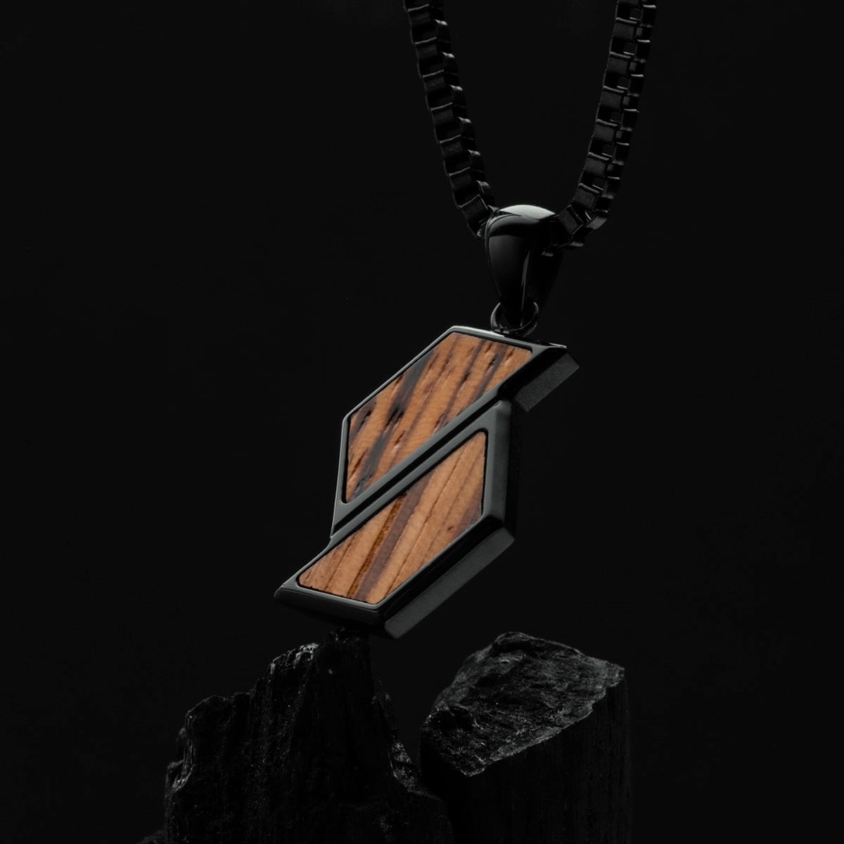"Baritone Necklaces": Zebrawood and black necklace with geometric design against a dark background.