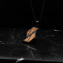 "Baritone Necklaces" necklace featuring zebrawood and black elements on a dark marble surface.