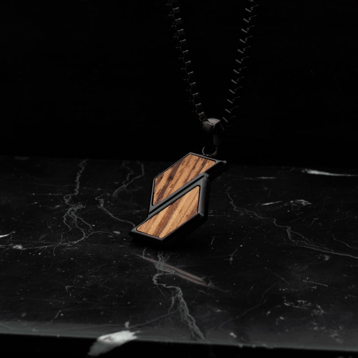 "Baritone Necklaces" necklace featuring zebrawood and black elements on a dark marble surface.