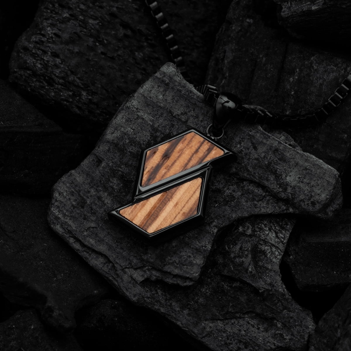 "Baritone Necklaces" necklace featuring geometric zebrawood and black design on dark textured background.