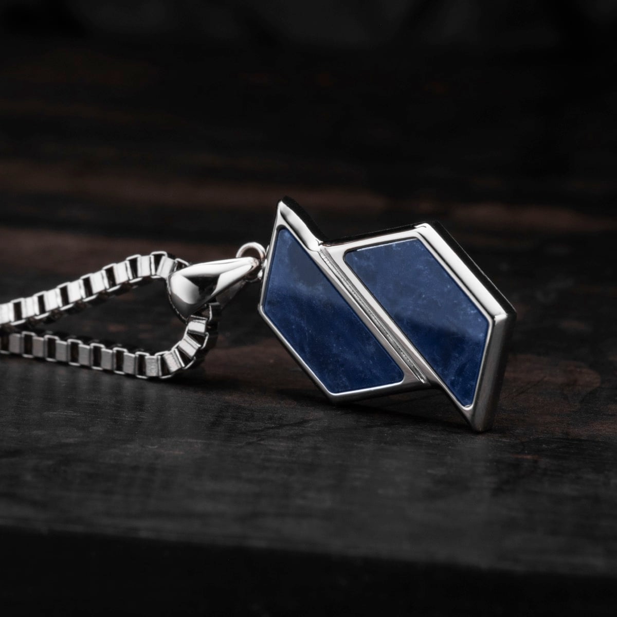"Baritone Necklaces" necklace features a sodalite stone in a silver setting with a geometric design on a dark background.