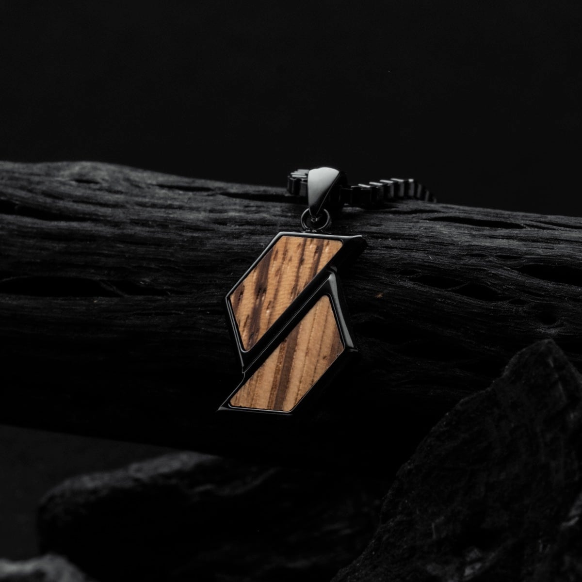 "Baritone Necklaces" necklace with geometric design in zebrawood and black finish, against a dark, textured background.