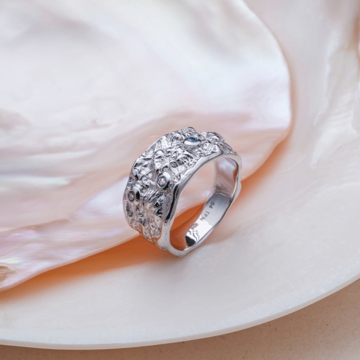 Silverstream Ring, a silver ring embellished with topaz stones, featuring an intricate textured design.