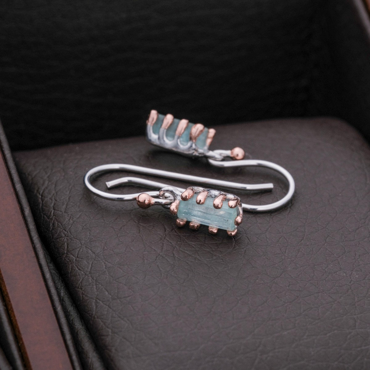 "Silverstream Earrings: Elegant rosegold earrings with aquamarine accents, featuring a modern, sleek design."