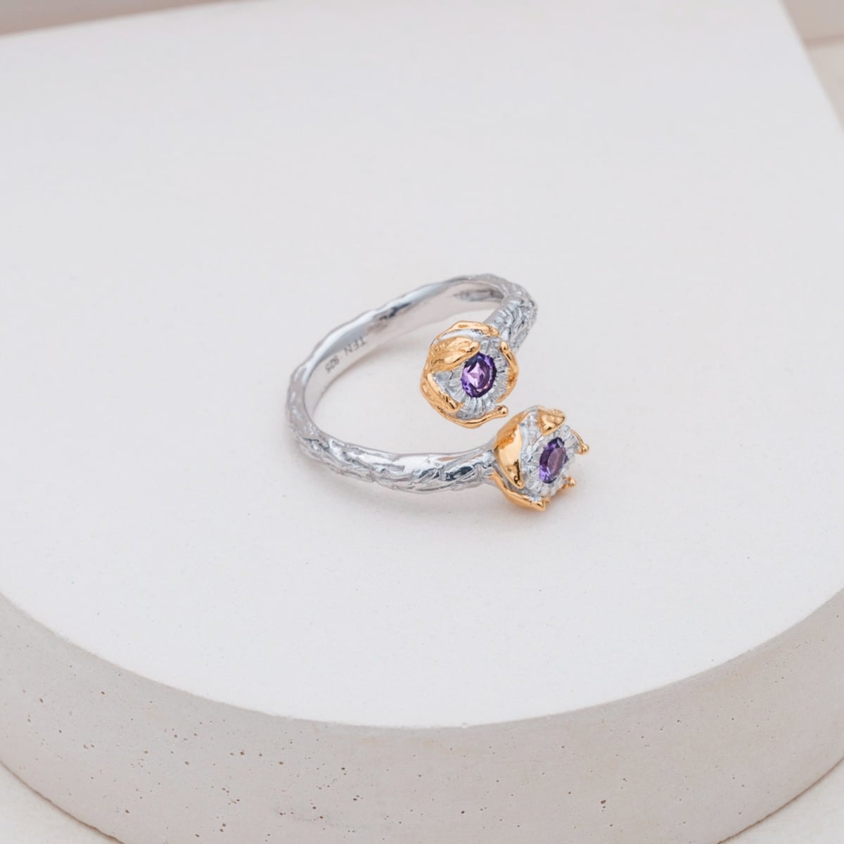 "Silverstream Ring": Elegant silver ring adorned with amethyst stones and gold accents, featuring a textured finish.