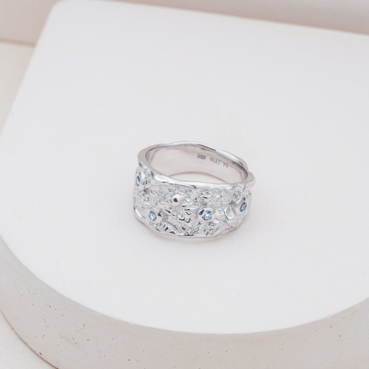 "Silverstream Ring", a textured silver ring adorned with sparkling topaz stones, exudes elegance and style.