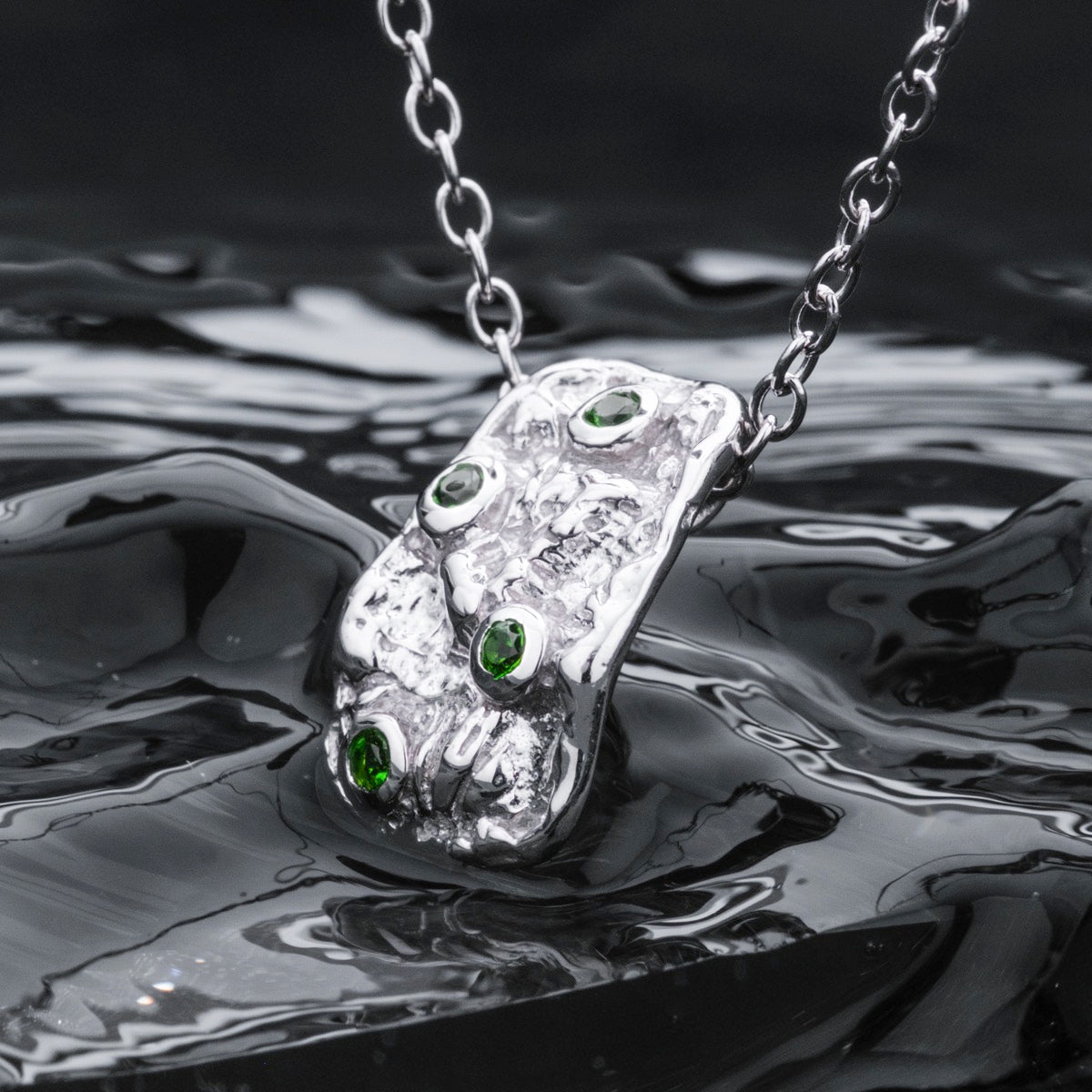 "Silverstream Necklace, a striking necklace with green diopside and silver design, set against a flowing water-inspired background."