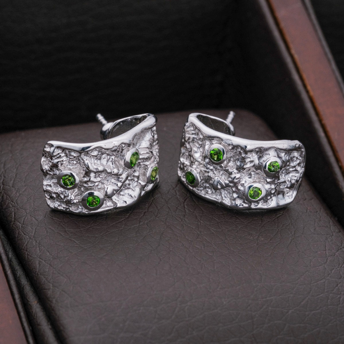 Silverstream earrings feature a textured silver design with green diopside accents, offering a modern, elegant style.