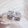 Silverstream earrings, elegant silver earrings with textured design and sparkling green diopside accents on a shell-like surface.