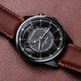 "Gmt Skywhirl" watch, featuring a marble and black design with a sleek, modern appearance on a brown leather strap.