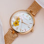 "Everbloom" watch with floral design, featuring plum blossoms and a gold mesh strap.