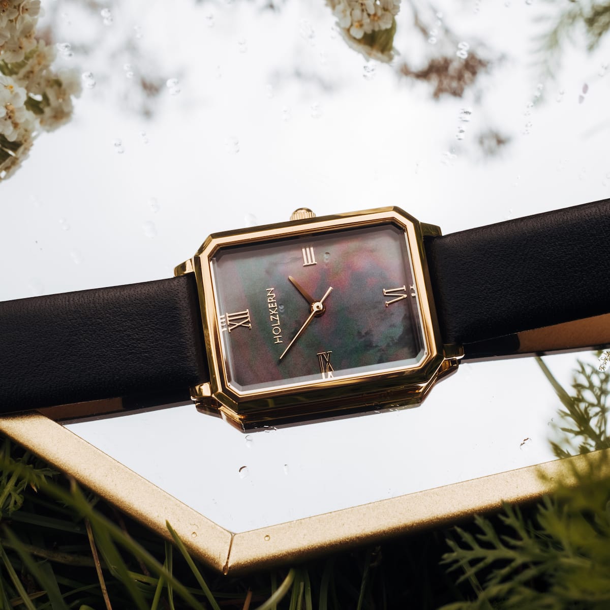 "Auctoritas" watch with a nacre face and gold accents, featuring a rectangular design and a black leather strap.