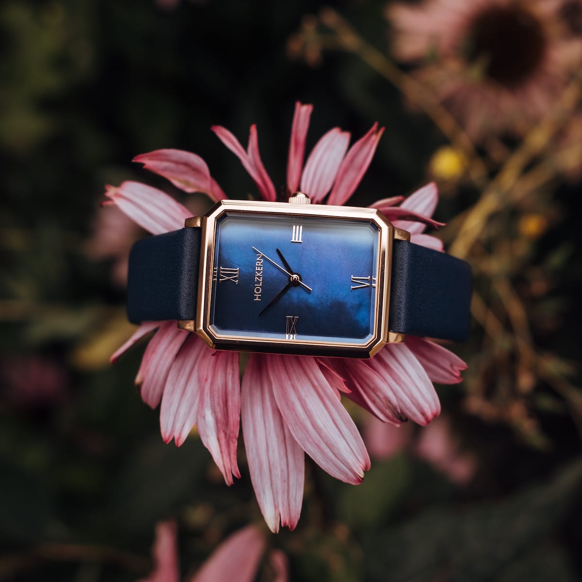 "Sapientia" watch with rose gold accents and a nacre-style face, set against a floral backdrop.